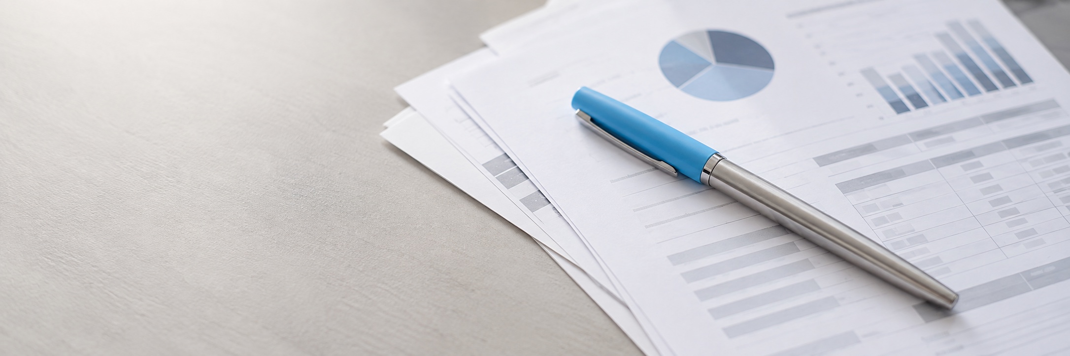 A silver pen with a light-blue cap resting on financial papers.